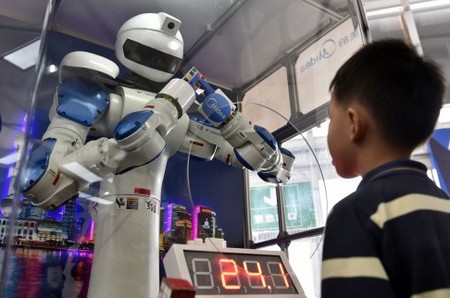 Robot đang thay thế con người làm nhiều việc, bao gồm cả những công việc đòi hỏi tư duy. Trong hình là cậu bé đang quan sát một robot giải khối rubik tại triển lãm công nghệ quốc tế tại tỉnh Quảng Đông